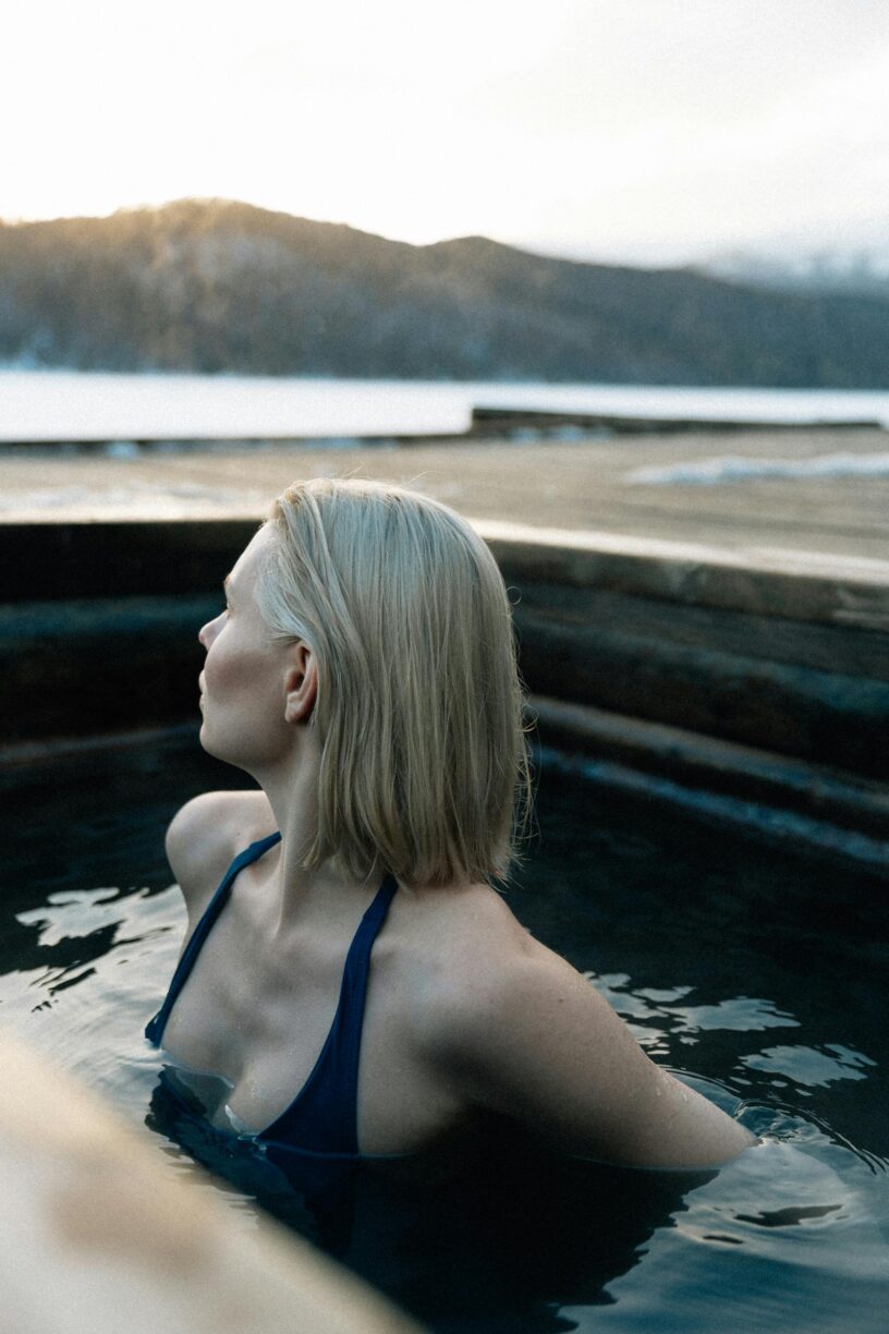 A lady with shoulder length blond hair immersed in a cold plunge bath